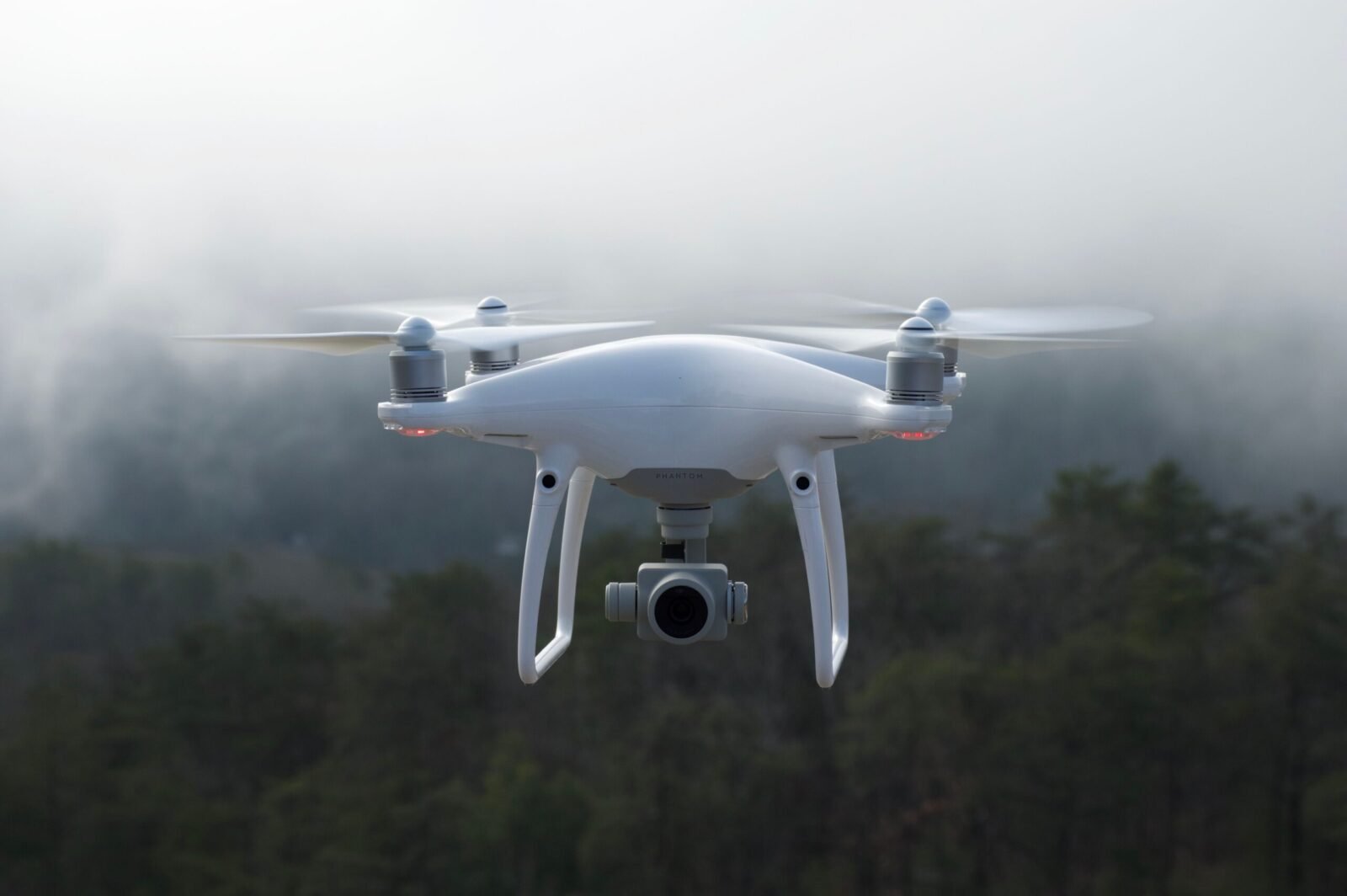 Drone hovering in a misty forest, capturing scenic aerial views.